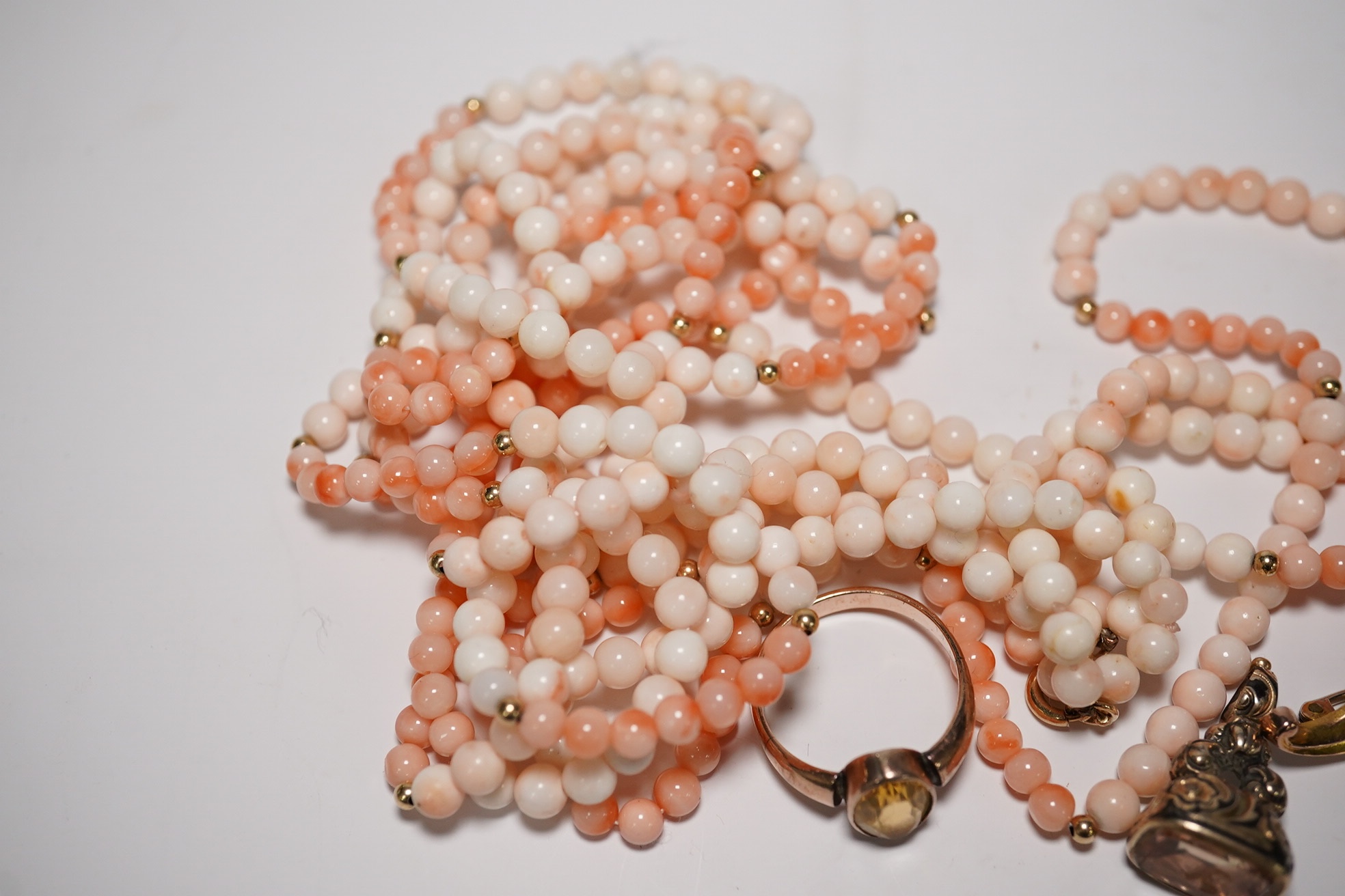 An Edwardian 9ct gold and gen set scroll brooch, 40mm, a yellow metal and gem set ring, a yellow metal overlaid fob seal and a modern coral bead necklace. Condition - poor to fair